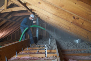 Male worker installing cellulose insulation in an attic