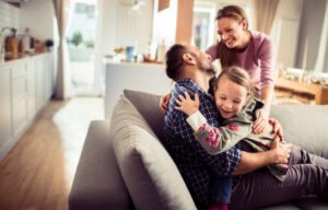 A joyful family embracing in a sunlit, energy-efficient home, symbolizing comfort and savings from improved insulation and energy use.